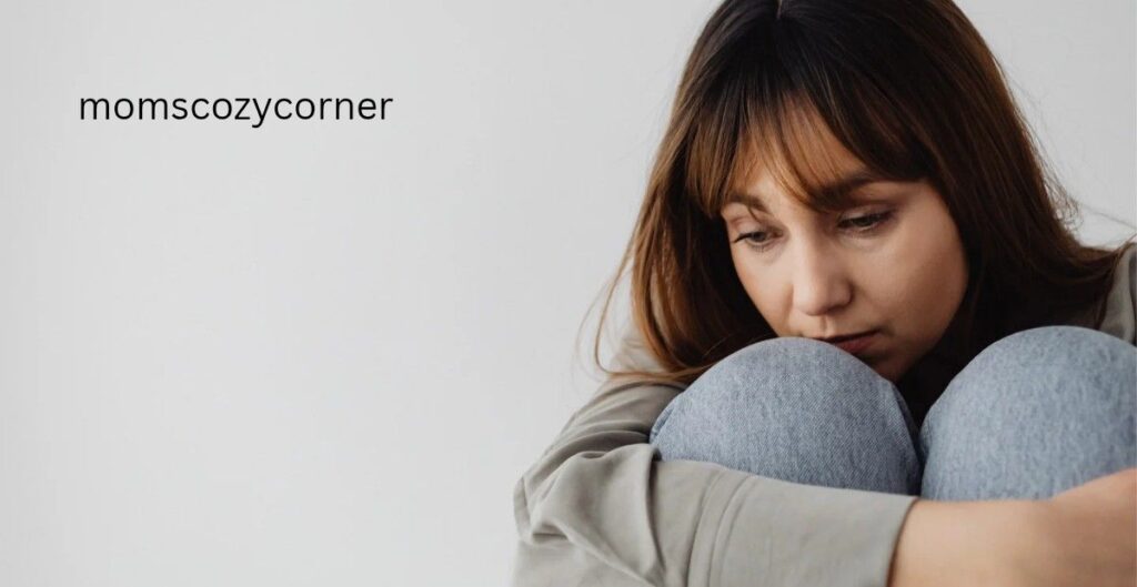 A sad woman sitting on the floor and holding her knees.